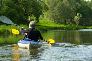 famille kayak voyage pour seigneur et madame. un personnes âgées marié couple aviron une bateau sur le rivière, une l'eau randonnée, une été aventure. liés à l'âge des sports, mental jeunesse et santé, tourisme, actif vieux âge photo