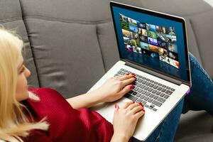 Jeune femme séance près le canapé en train de regarder vidéo sur portable photo