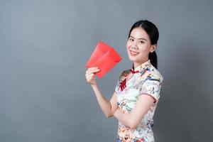 une femme asiatique porte une robe traditionnelle chinoise avec une enveloppe rouge ou un paquet rouge photo