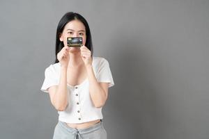 femme asiatique avec un visage heureux et présentant une carte de crédit en main montrant la confiance pour effectuer le paiement photo