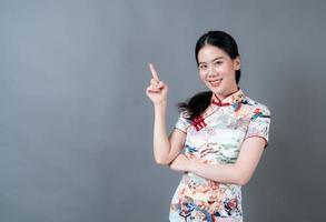 belle jeune femme asiatique porter une robe traditionnelle chinoise avec la main présentant sur le côté