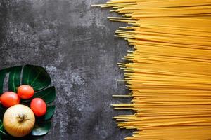longs spaghettis jaunes sur fond rustique. pâtes italiennes jaunes. longs spaghettis. spaghettis crus à la bolognaise. spaghettis crus. concept de fond de nourriture. concept de cuisine et de menu italien. photo