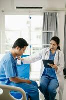 asiatique médecin dans blanc costume prendre Remarques tandis que discuter et asiatique âgé, homme patient qui mensonge sur lit avec recevoir saline Solution dans hôpital. photo