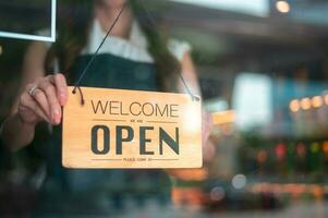 femme entrepreneur avec ouvert signe dans café magasin , petit affaires concept photo