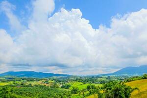 gros nuage plein de ciel sur le Montagne et vert champ brillant couleurs dans pays photo