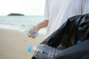 enregistrer océan. bénévole choisir en haut poubelle des ordures à le plage et Plastique bouteilles sont difficile décomposer prévenir nuire aquatique vie. Terre, environnement, écologisation planète, réduire global échauffement, enregistrer monde photo