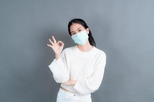 jeune femme asiatique portant un masque médical et montrant un signe ok photo