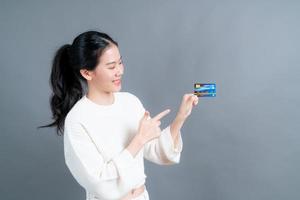 portrait d'une jolie jeune femme asiatique en pull montrant une carte de crédit avec espace de copie photo