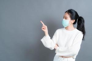 jeune femme asiatique portant un masque médical et pointant du doigt