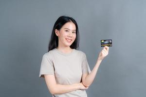 portrait d'une jolie jeune femme asiatique montrant une carte de crédit photo