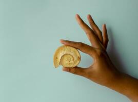 Jeune asiatique femmes en portant mini vanille rouleau gâteau, Suisse rouleau gâteau ou éponge rouleau avec vanille saveur. thaïlandais appel confiture Rouleaux. isolé sur bleu Contexte photo