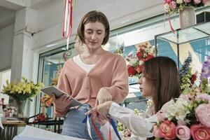 deux Jeune magnifique femelle fleuriste les partenaires discuter Floraison bouquet arrangement conception dans tablette, en ligne achat commande travail dans coloré fleur magasin boutique avec Frais flore, pme affaires entrepreneur. photo