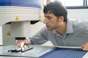 La technologie concept une homme au travail ingénieur panneau planche ic électronique microscope à travail avec une puce électronique. électronique recherche laboratoire. fabrication de puces. équipement pour essai photo