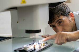 La technologie concept une homme au travail ingénieur panneau planche ic électronique microscope à travail avec une puce électronique. électronique recherche laboratoire. fabrication de puces. équipement pour essai photo