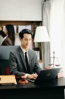 asiatique avocat homme travail avec une portable et tablette dans une loi bureau. légal et légal un service concept. à la recherche à caméra dans moderne Bureau photo