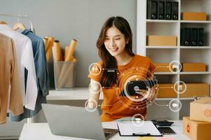 femme main en utilisant une ordinateur portable, téléphone intelligent et tablette et l'écriture carnet à le Bureau de sa affaires en ligne achats. dans Accueil avec virtuel icône photo