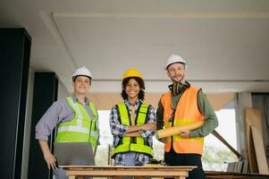 ingénieurs sont discuter Les données travail et portable ou tablette avec architectural projet à Nouveau construction site sur gros projet. photo