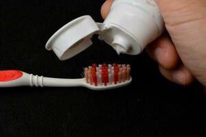 blanc dentifrice sur une brosse à dents. noir Contexte photo