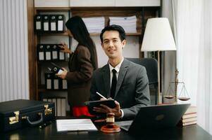 asiatique avocat homme travail avec une portable et tablette dans une loi bureau. légal et légal un service concept. à la recherche à caméra dans moderne Bureau photo