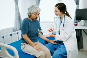 femme médecin et patient discuter quelque chose tandis que séance sur examen lit dans moderne clinique ou hôpital . médicament et santé se soucier concept. photo