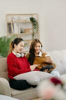 deux asiatique élèves apprentissage ensemble en ligne avec une ordinateur portable, tablette et tuteur ensemble dans vivre pièce photo