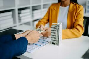 agent de courtage immobilier présentant et consultant le client pour la prise de décision signe un accord de formulaire d'assurance, modèle de maison, concernant l'offre de prêt hypothécaire au bureau photo