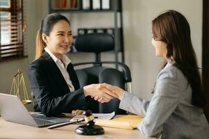 la main d'une avocate et une cliente se serrant la main collaborent sur des accords de travail avec des documents contractuels au bureau moderne. photo