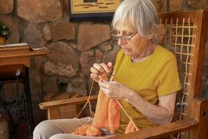 portrait de un personnes âgées femme tricot à maison. photo