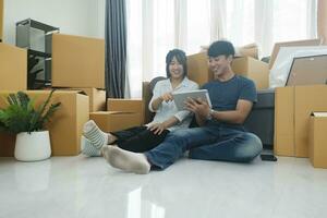 content couple avec papier carton des boites dans Nouveau maison à en mouvement journée. photo