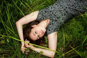 brunette femme mensonge sur vert herbe. beauté fille en plein air profiter la nature et relaxation. gratuit content femme, Haut vue photo