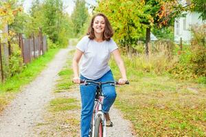 jeune femme à vélo dans le parc de la ville d'été à l'extérieur. personnes actives. fille hipster se détendre et faire du vélo. faire du vélo au travail le jour de l'été. concept de mode de vie vélo et écologie. photo