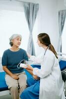 femme médecin et patient discuter quelque chose tandis que séance sur examen lit dans moderne clinique ou hôpital . médicament et santé se soucier concept. photo