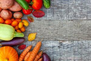 assortiment de différents légumes biologiques frais sur fond en bois de style campagnard. concept de régime végétarien végétalien d'aliments sains. jardin local produit de la nourriture propre. vue de dessus du cadre espace de copie à plat. photo