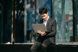 sur de soi asiatique homme avec une sourire permanent en portant bloc-notes et tablette à le moderne bureau. photo