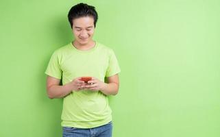 Portrait d'homme asiatique en t-shirt vert posant sur fond vert