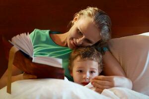jeune mère lisant à son enfant au lit photo