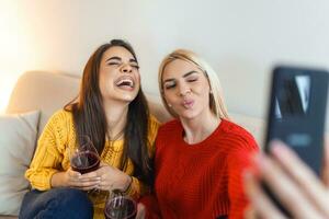 excité copains prise selfie et en riant. intérieur coup de deux émotif caucasien filles. deux adulte femme fabrication selfies avec marrant visages. deux femelle copains prise une selfie photo