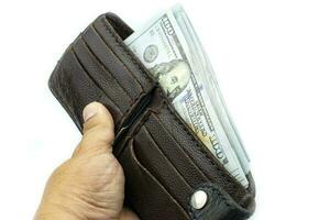 Hand holding wallet sur des liasses de billets de 100 dollars américains sur fond blanc photo