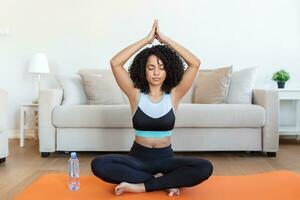 jeune femme souriante séduisante pratiquant le yoga, assise dans un exercice de demi-lotus, pose d'ardha padmasana, s'entraînant, portant des vêtements de sport, séance de méditation, pleine longueur intérieure, intérieur de la maison photo