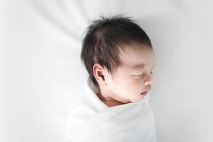 nouveau-né dormant dans une couverture blanche. photo