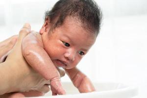 nouveau-né est baigné par sa mère à l'aide d'une baignoire à la maison. photo