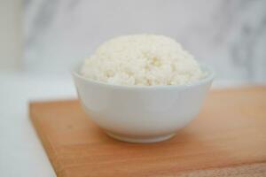 cuit riz dans une blanc bol sur une en bois planche. sélectif se concentrer. photo