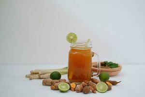 Frais gingembre et citron jus dans une verre pot avec gingembre les racines sur blanc Contexte. photo