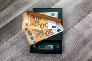 billets en euros sur le dessus d'une balance avec cigare