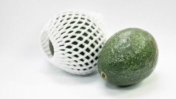 vert Avocat fruit et rugueux peau. des fruits sont couvert avec antichoc mousse avec une engrener modèle pour côté beauté. isolé blanc Contexte. photo