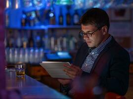 homme d'affaire avec tablette PC et whisky à le bar compteur photo