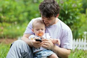 père en portant une bébé et envoyer des SMS sur le sien mobile photo