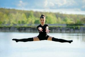 Jeune gymnaste est en haut dans le air Faire jambe fendue photo