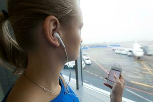 Femme écoutant de la musique par la fenêtre à l'aéroport photo