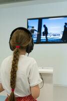 une enfant avec écouteurs écoute à musique. une fille dans noir écouteurs écoute à la musique et montres la télé. photo
